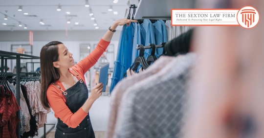 Female retail worker hanging clothes on a clothes display at a store